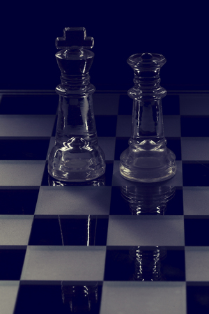 King and queen glass chess pieces facing each other in black and whiteの写真素材