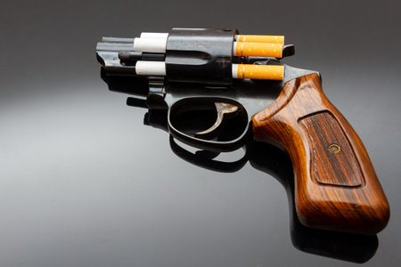 Dangerous short revolver with cigarettes as bullets on shiny surfaceの写真素材