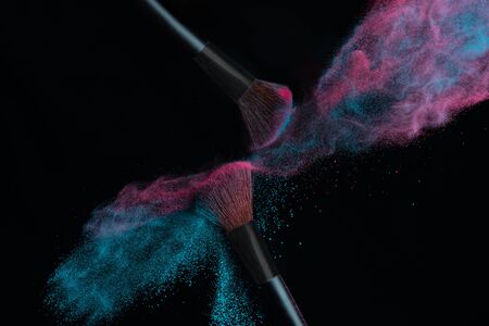 Two brushes with pink and blue make up powder impact to make a cloudの写真素材