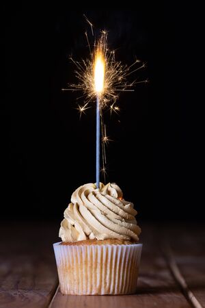 One cupcakes on a table with a sparkle and a black backgroundの写真素材