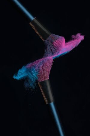 Two brushes with pink and blue make up powder impact to make a cloudの写真素材