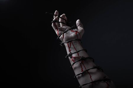 Concept photo of a hand and arm tied with barbed wire in studio artistic conversionの写真素材
