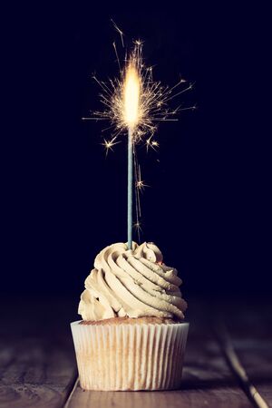 One cupcakes on a table with a sparkle and a black backgroundの写真素材