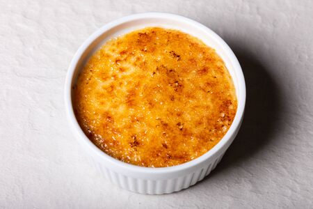 Fresh crÃ¨me brulee in a small white bowl close-up on tableの写真素材