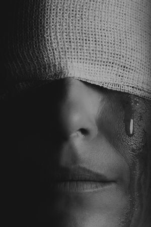 Conceptual photo of a hurt woman crying with a bandage around her head artistic concersionの写真素材