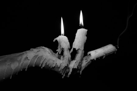 A human hand transformed into a candelabra, its fingers dripping in wax and aflame, captures the emotional toll of constant giving.の写真素材