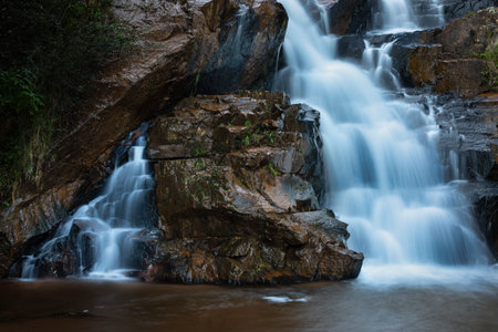 Waterfall flowing over large rock formations, long exposure capturing the silky flow of waterの写真素材