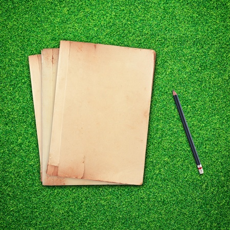 Pencil and old book on green grass backgroundの写真素材