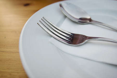 fork and spoon with white plate on wood tableの写真素材
