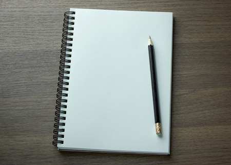 blank spiral notebook and pencil on dark wood backgroundの写真素材