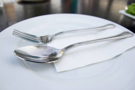 spoon and fork with white plate on tableの写真素材