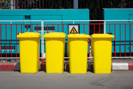 Yellow garbage bin in the street beside the walkwayの写真素材