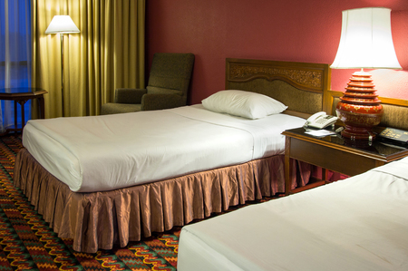 Double bed with table lamp in the bedroom at night timeの写真素材