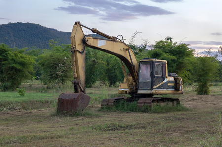 Abundant backhoe on construction site in the green fields with sunsetの写真素材