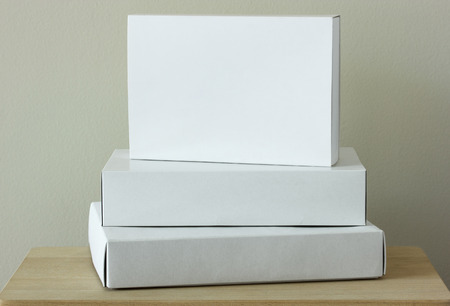 Stack of white cardboard package box mockup on wooden tableの写真素材