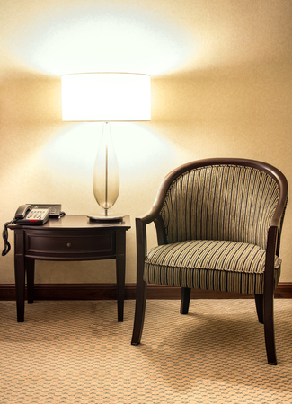 Table lamp with wooden chair in the bedroom at night timeの写真素材