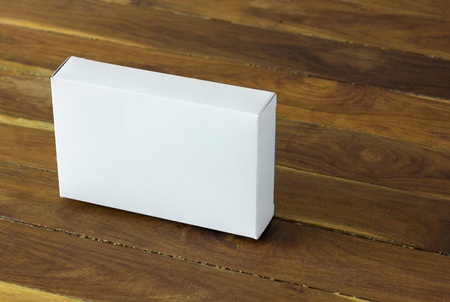 blank white cardboard package box mockup on dark wooden tableの写真素材