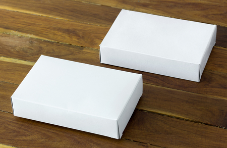 blank white cardboard package box mockup on dark wooden tableの写真素材