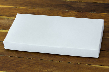 blank white cardboard package box mockup on dark wooden tableの写真素材