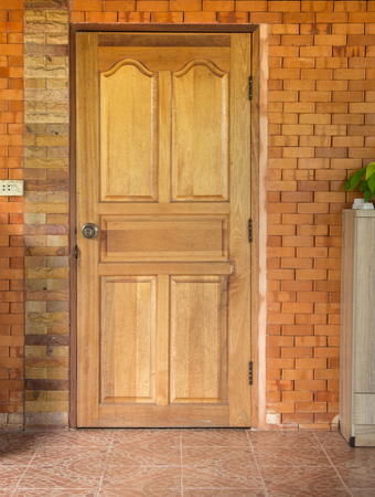 wooden door in brick wall background at homeの写真素材
