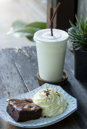 brownie cake with whipped cream and tea on the tableの写真素材