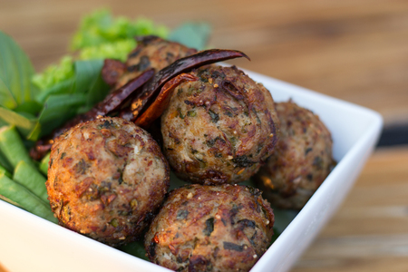 spicy mince pork balls with salad in a white plate on the table. Thai food (Larb Moo Tod)の写真素材
