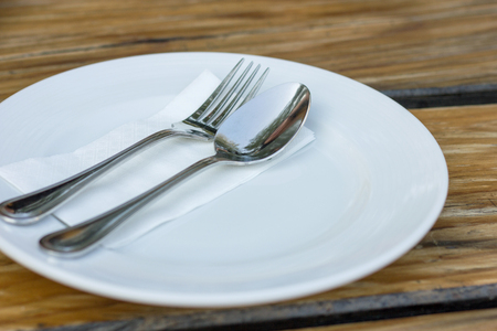 fork and spoon with white plate on wood tableの写真素材