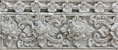 Pattern of gray flower carved on stucco design of native wall, Thai style in templeの写真素材