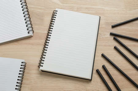 blank spiral notebook with pencil on wooden table for mockup blank templateの写真素材
