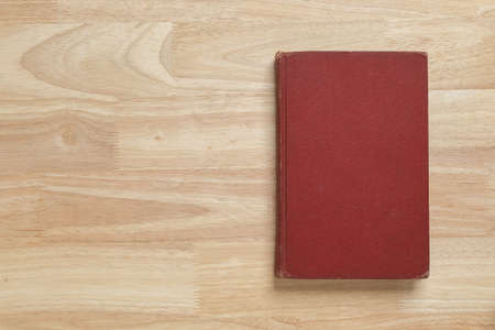 red hardcover book on wooden table for mockup blank templateの写真素材