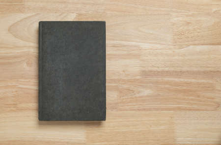dark old book cover on wooden table for mockup blank templateの写真素材