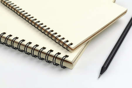 Close up spiral notebook and black pencil on white background for mockup blank templateの写真素材