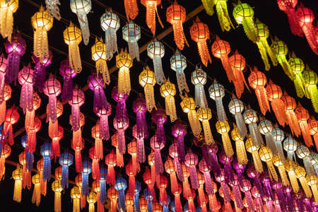 colorful hanging lanterns lighting on night sky in loy krathong festival at northern of thailandの写真素材