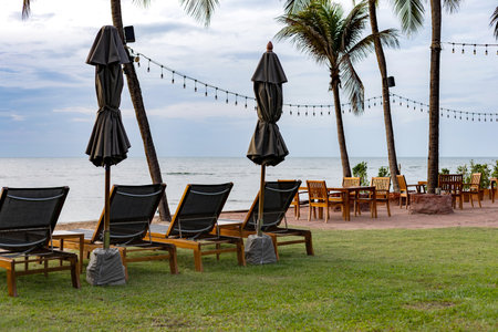back view of beach chairs and umbrella with sunset on tropical vacation at sea in thailandの写真素材