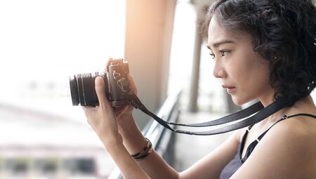 young woman using a camera to take photo outdoors at balcony buildingの写真素材