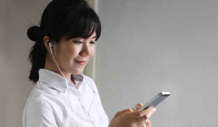 young beautiful asian woman girl in casual wear relaxing and listening music headphones indoorの写真素材
