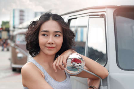 Beautiful woman relaxing outdoor, touching on van's rearview mirrorの写真素材