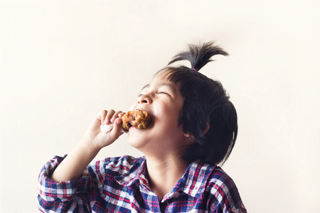 cute little asian boy eating fried chicken and laugh on vintage color backgroundの写真素材