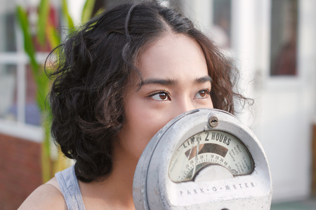 Attractive woman and parking meter on street outdoors backgroundの写真素材