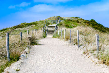 Empty sandy path with stairs through dunes leading to the beach. Summer. Vacation. The Netherlands. Travel. Path to unknown. Journey. Adventure. Destinationの写真素材