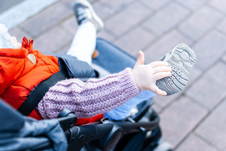 Active toddler girl enjoying her ride in a stroller. Close up of a toddler shoe. Comfortable toddler...