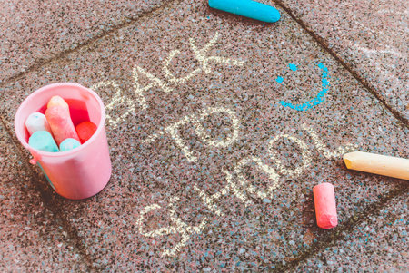 An composition with a bucket of colorful chalks and chalks lying on pavement around Back to school...