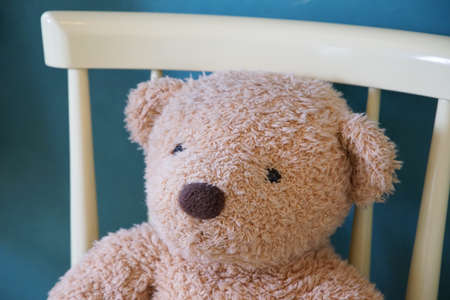 Stuffed toy of the bear sitting down on the chair of the roomの写真素材