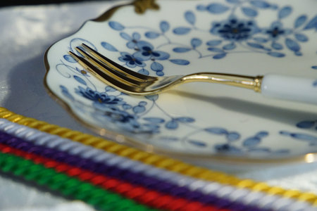 A fork of the tableware on the table and a plate and colorful string