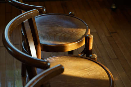 The setting sun illuminates the room round wooden chairの写真素材