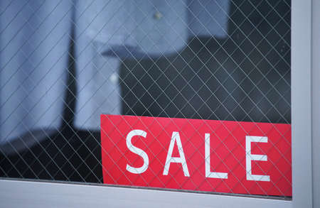 The red signboard which was written as a sale placed in the window of the storeの写真素材