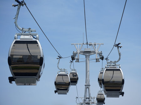 Many cable car gondolas hanging from the cables on a sunny blue sky day