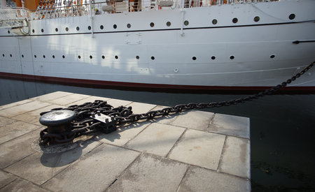 A sailing ship moored in the harbor with a chain