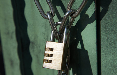 Dial lock hanging on the chain of an outdoor gate