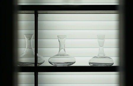 Glass vases on a shelf with blinds in the background.の写真素材